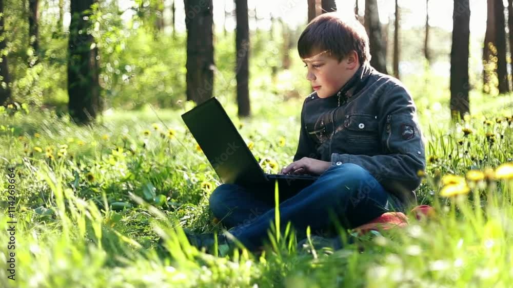 Teen boy child with a PC laptop, communicate via Internet by notebook outdoor Teen boy child with a PC laptop, communicate via Internet by notebook outdoor