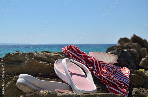 Swimsuit and flip flops left on the rocks by the sea