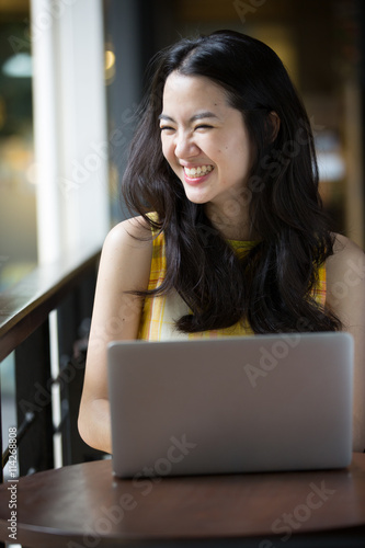 Asian woman happily using a notebook