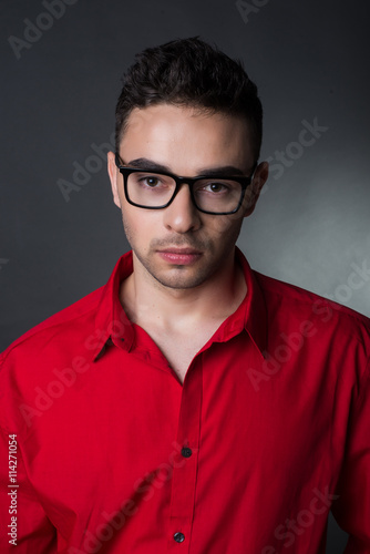 Man on black background in red shirt and glasses. Business style