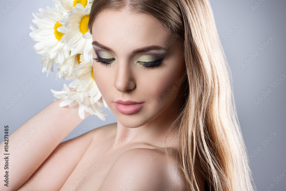 Portrait of a young attractive girl with a beautiful make-up and daisies.