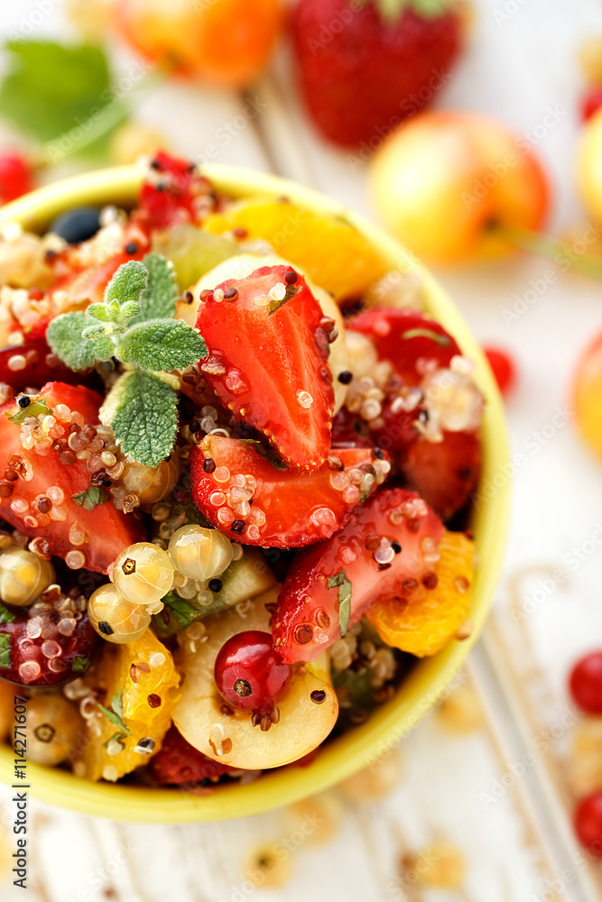 Fruit salad with the addition of quinoa, honey, lemon juice and mint in a ceramic bowl on a wooden table Fruit salad with the addition of quinoa, honey, lemon juice and mint in a ceramic bowl on a wooden table