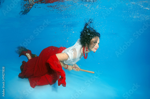 A young woman with big hair posing in a pool underwater