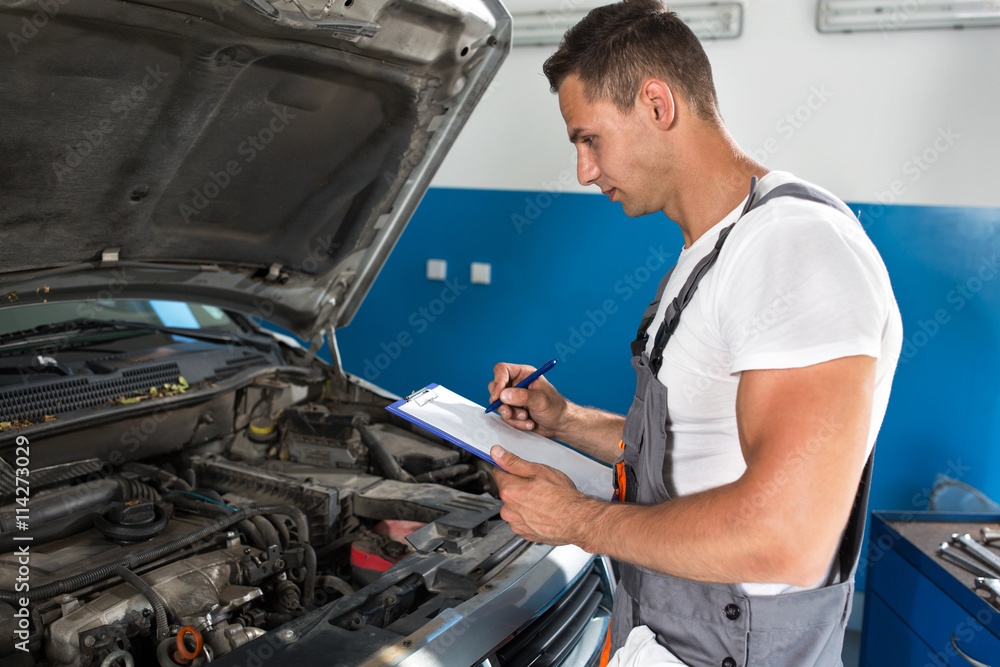 Mechanic man holding clipboard and check the car Mechanic man holding clipboard and check the car