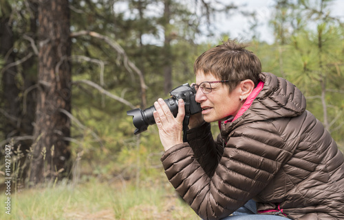 Happy Mature Woman Taking Photos with a Digital DSLR Camera Outdoors