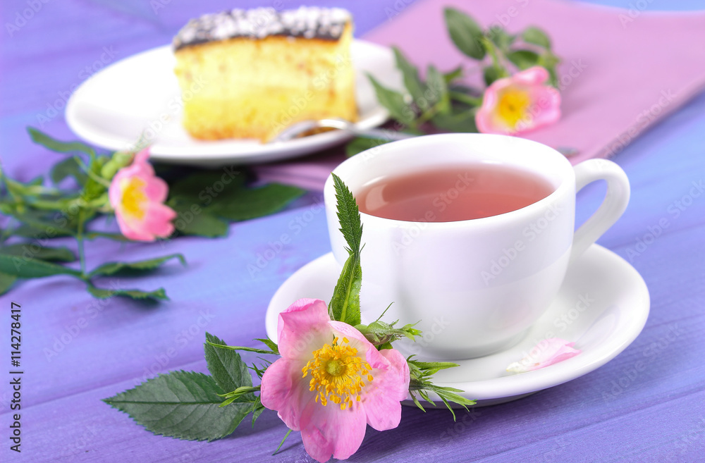 Cup of tea with cheesecake and wild rose flower on purple boards Cup of tea with cheesecake and wild rose flower on purple boards