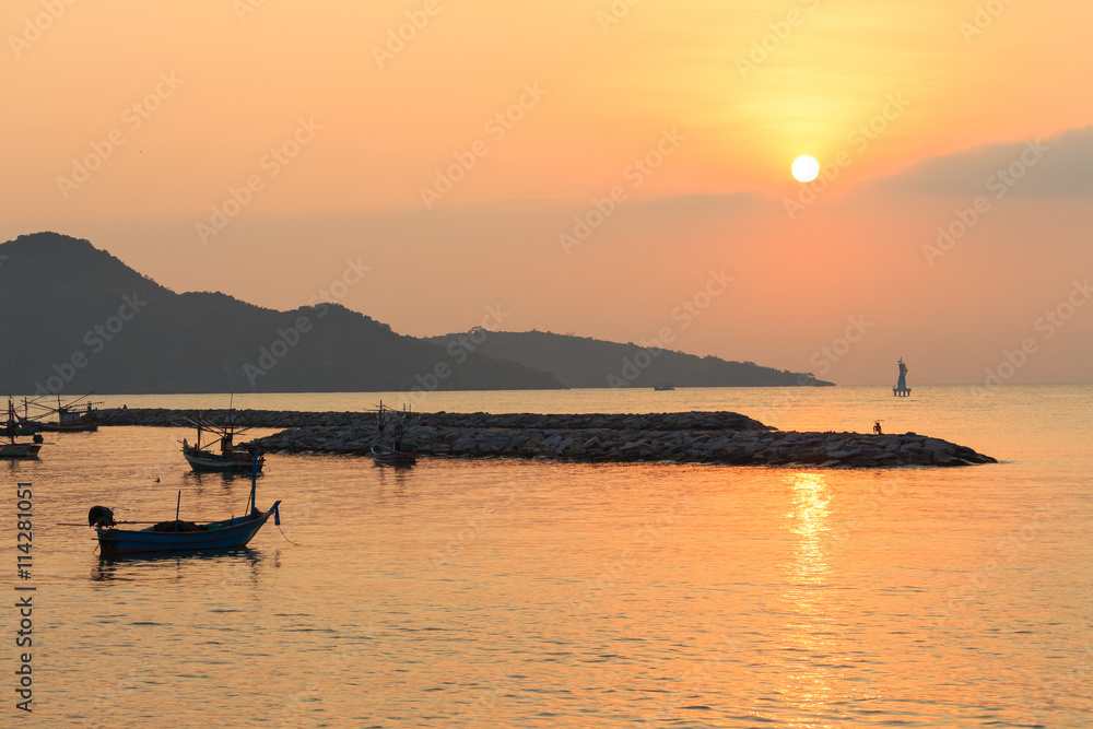 sunrise at sea. variety of colors and hues of the rising sun, Reflections on the sea,There are boats and bicycles on a small rocky island. Behind have  mountains.