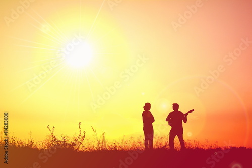 Silhouette people playing musical in the sunset