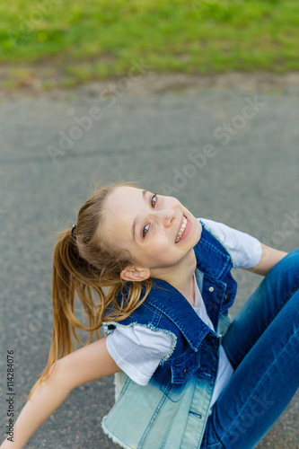 portrait of a beautiful smiling girl sitting on the asphalt