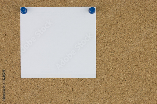 Note paper with push pins on cork board.
