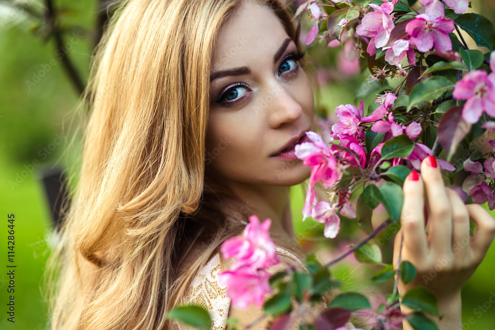 beautiful young woman in a summer dress near blooming trees