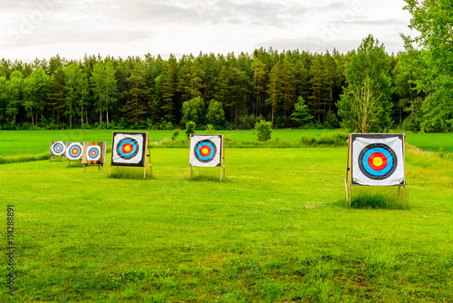 Fotografering Outdoor archery targets on grass field surrounded by forest in the summer evening