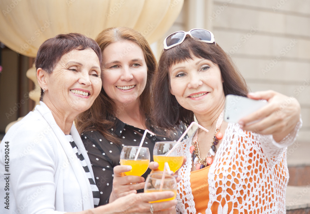 Three mature women friends doing selfie on a mobile phone Three mature women friends doing selfie on a mobile phone