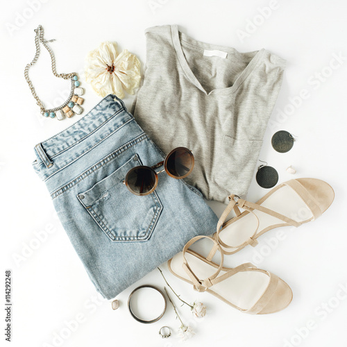 flat lay feminini clothes and accessories collage with shirt, jeans shorts, sunglasses, bracelet, sandals, earrings on white background.