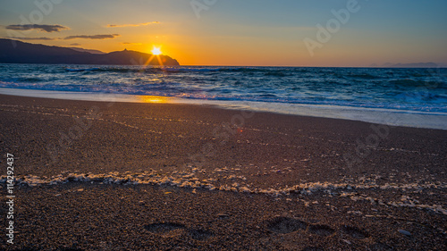 Sunrise at Tinderi beach with foodprints in the sand photo