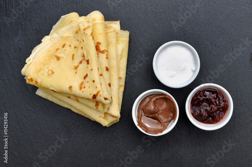 crêpes et pots de confiture, sucre et chocolat sur fond ardoise