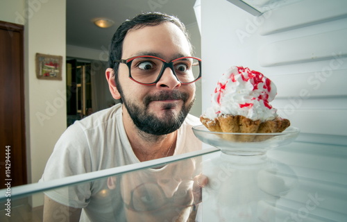 funny man sees the sweet cake in the fridge photo