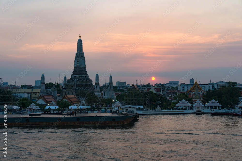 Aerial view of Wat Arun, Temple of Dawn and wharf with sunset sky on the background. Urban Bangkok scene with Buddhist temple
