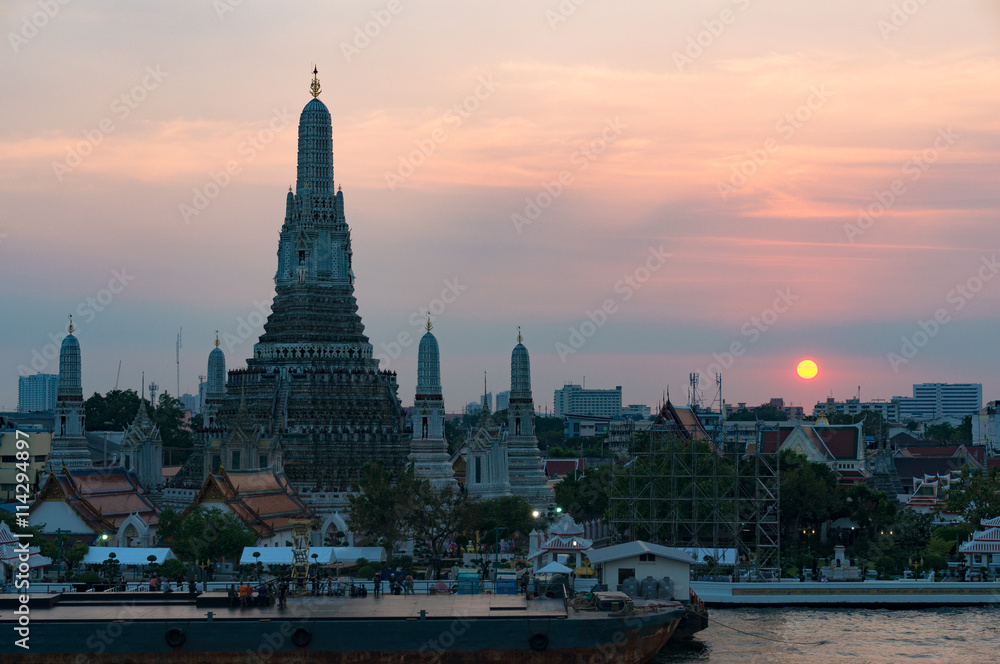 Fototapeta premium Aerial view of Wat Arun, Temple of Dawn and wharf with sunset sky on the background. Urban Bangkok scene with Buddhist temple