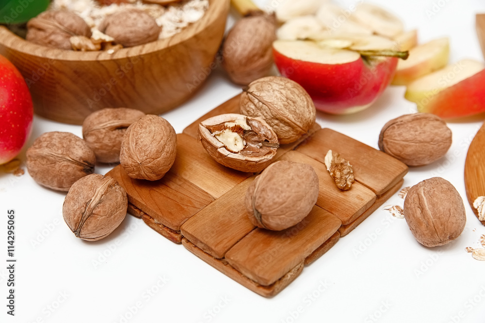 There are Banana,Apple,Orange with Walnuts in the Wooden Plate,Trivet,Healthy Fresh Organic Food on the White Background,Selective Focus There are Banana,Apple,Orange with Walnuts in the Wooden Plate,Trivet,Healthy Fresh Organic Food on the White Background,Selective Focus