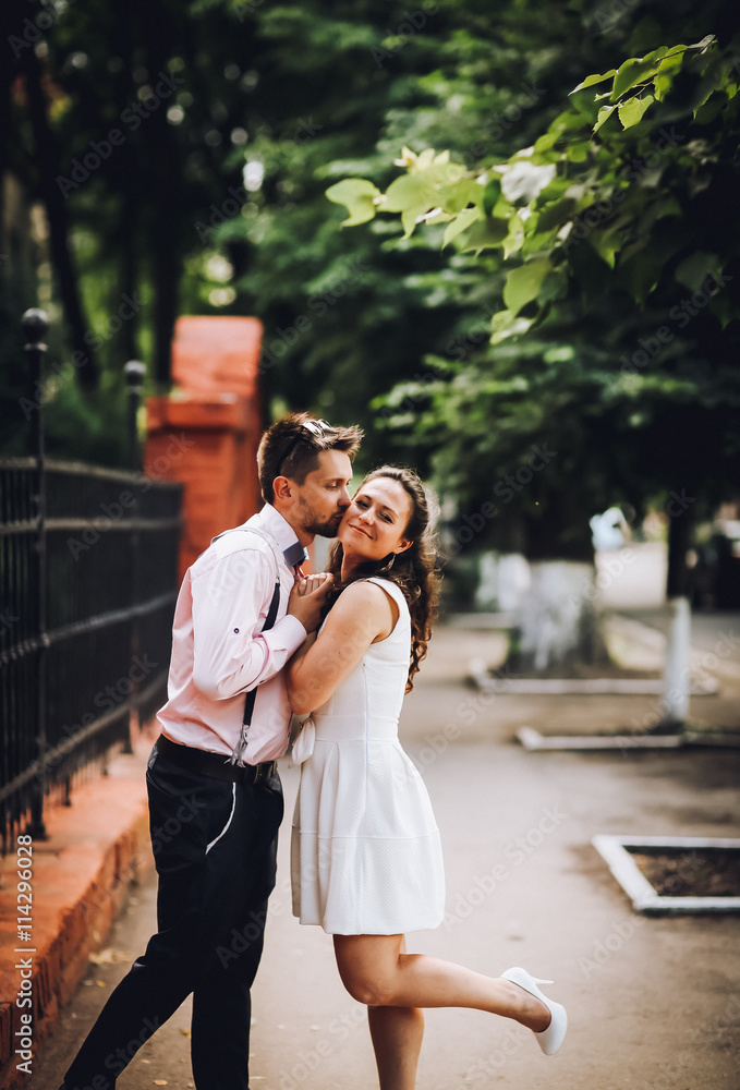 Young pretty colored portrait of young couple in love posing in evening in city and having fun together