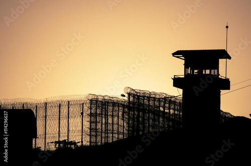 Silhouette of barbed wires and watchtower of prison in Neapolis, Crete, at sunset  photo