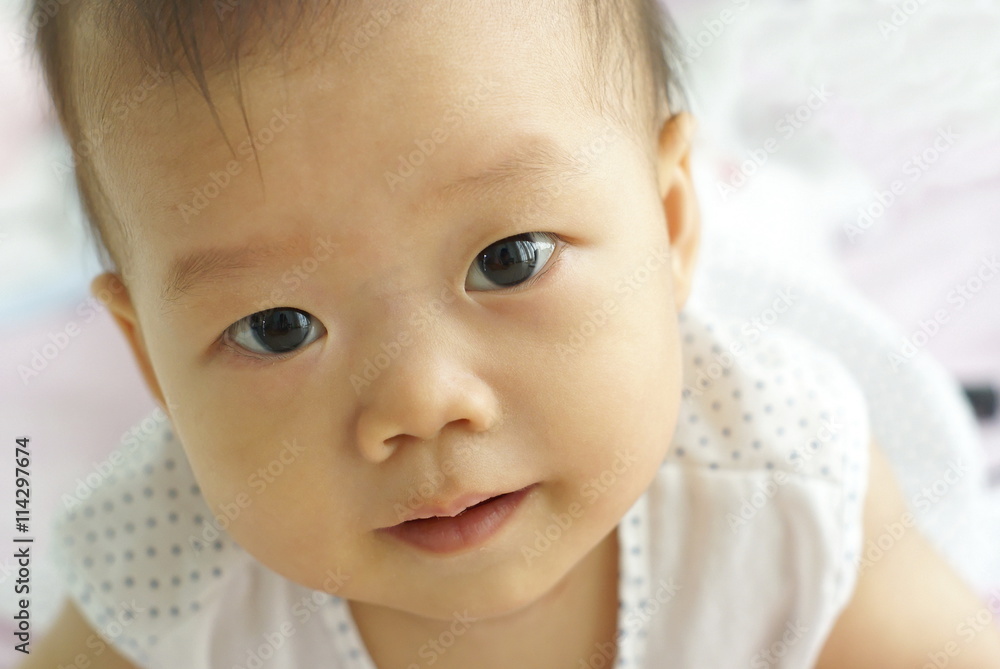 Face of cute Asian infant looking to someone.