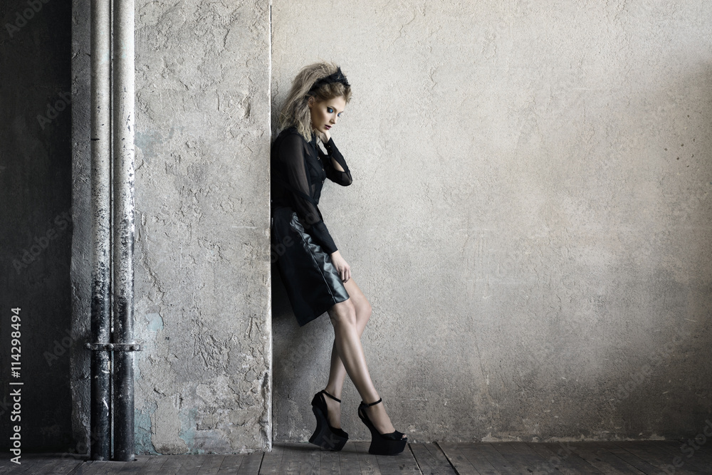 Fototapeta premium Tall model posing in studio in dark midi leather skirt