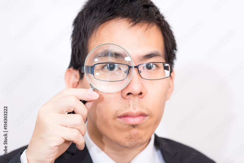 Business asian man Looking At camera Through Magnifying Glass