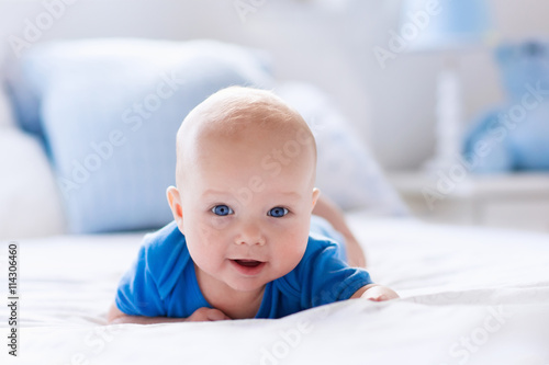 Baby boy in white sunny bedroom