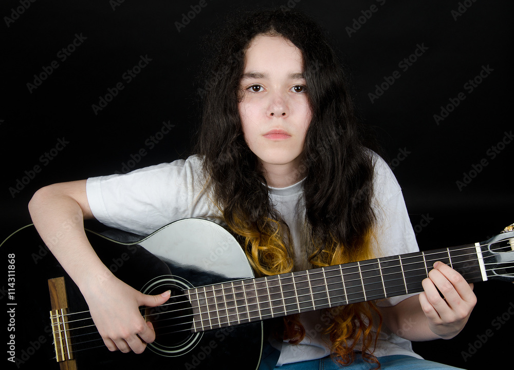 Teenage girl with painted hair playing a black guitar (on a black background) Teenage girl with painted hair playing a black guitar (on a black background)