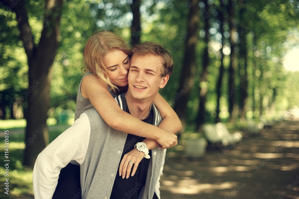 Happy young couple. Beautiful smiling blonde girl hugging her boyfriend from the back. Happy young couple. Beautiful smiling blonde girl hugging her boyfriend from the back.