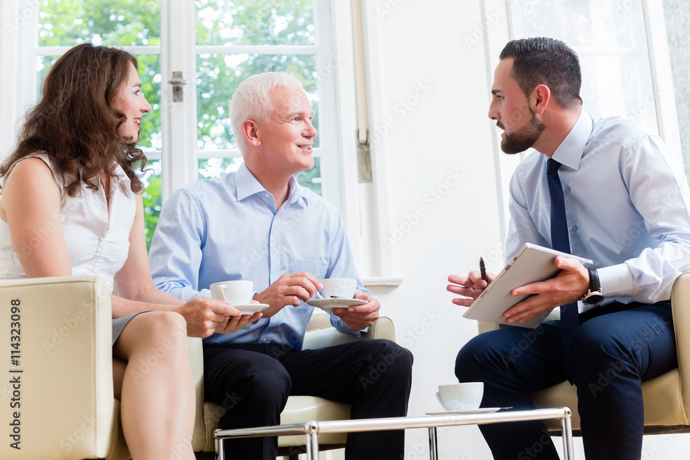 Finanzberater berät Mann und Frau zu Versicherung und Geldanlage in modernem Büro Finanzberater berät Mann und Frau zu Versicherung und Geldanlage in modernem Büro