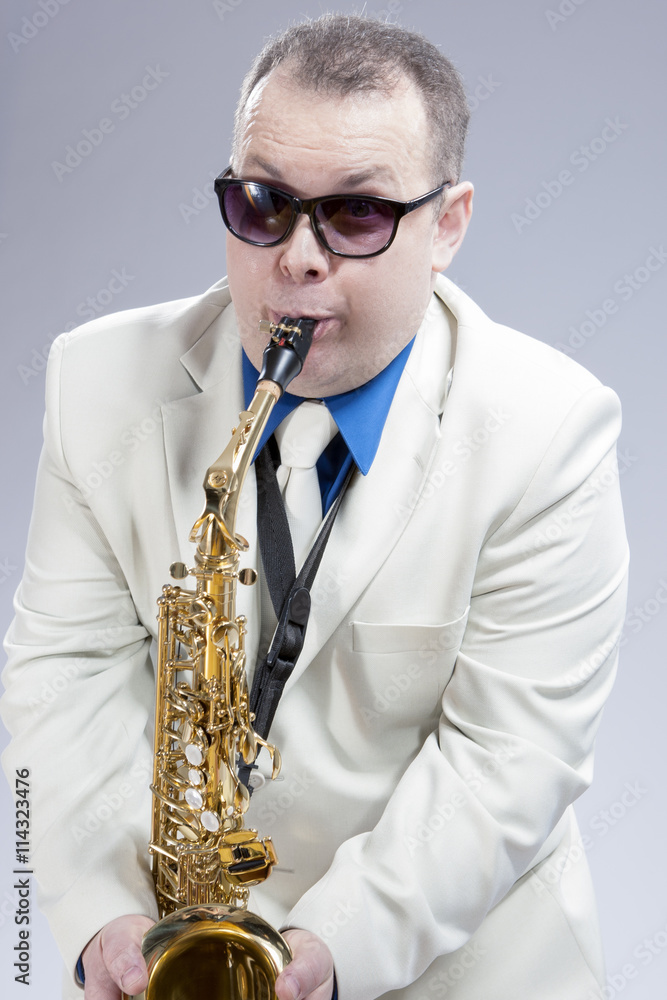 Fototapeta premium Portrait of Funny Caucasian Saxophone Player in Sunglasses Performing Indoors