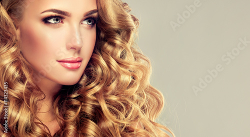 Beautiful girl with long wavy hair . Blonde model with curly hairstyle . 