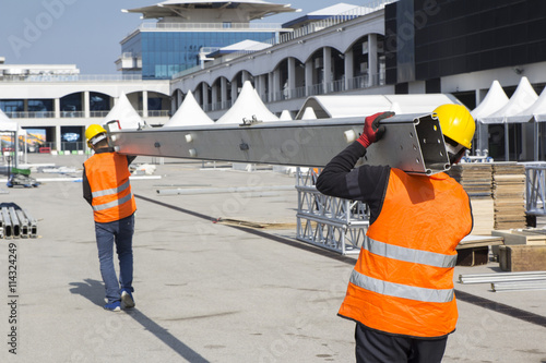 workers carry construction metal pipes