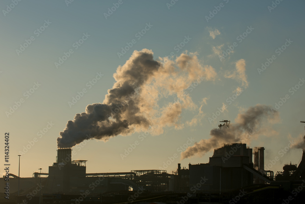 Sunset at steel factory showing smoke chimneys