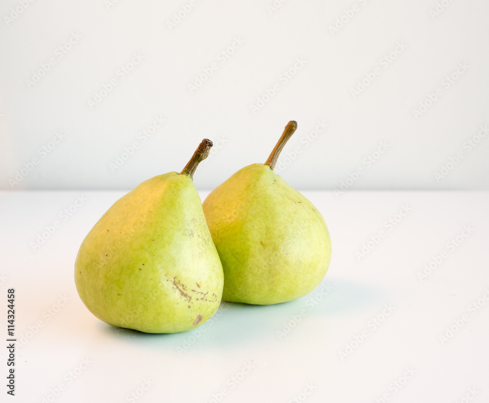 High angle view of two natural looking green pears on a white table High angle view of two natural looking green pears on a white table