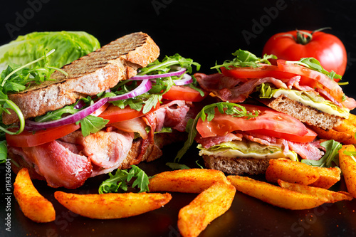 Fresh homemade BLT sandwich on grilled bread with bacon, lettuce, beef tomato, red onions, wild rocket and chips