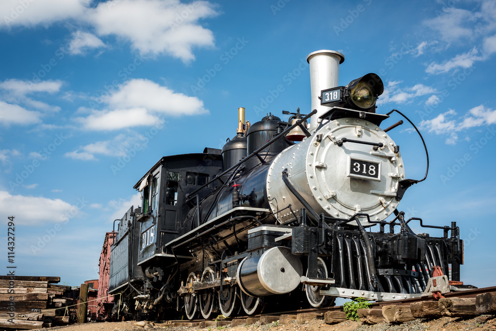 Fototapeta premium Old train engine from the west with blue sky and clouds