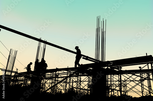 Quadro su tela Silhouette of construction workers working on scaffolding at a h
