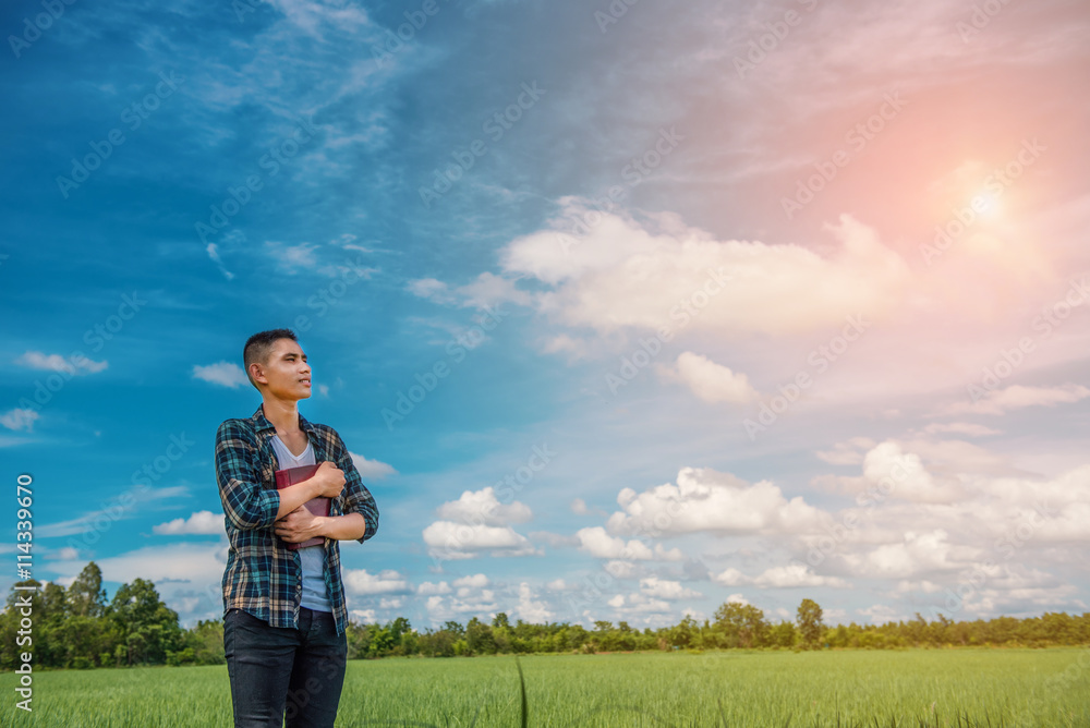 Young man holding book in the green meadow. Free happy man. Knowledge is power. Thirst for knowledge. Young man holding book in the green meadow. Free happy man. Knowledge is power. Thirst for knowledge.