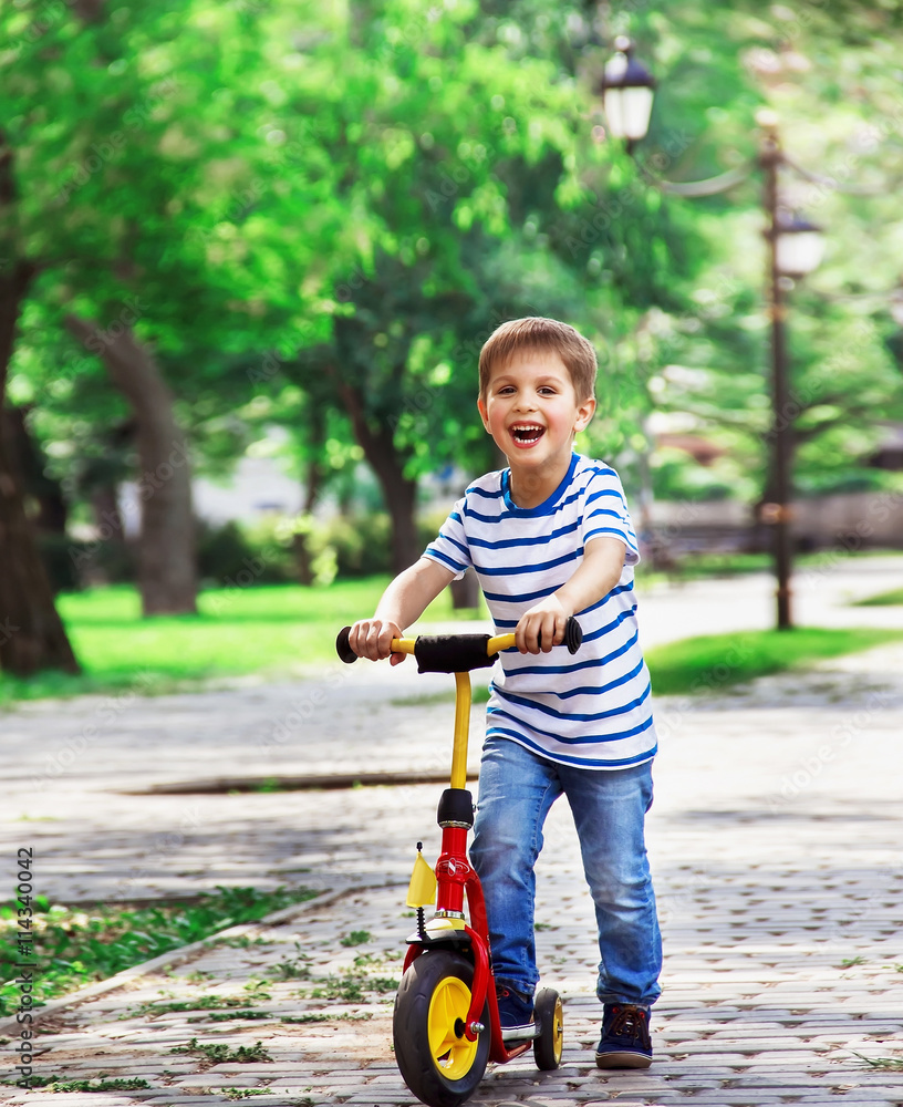 cheerful boy on a scooter, playing in the park on a background o cheerful boy on a scooter, playing in the park on a background o