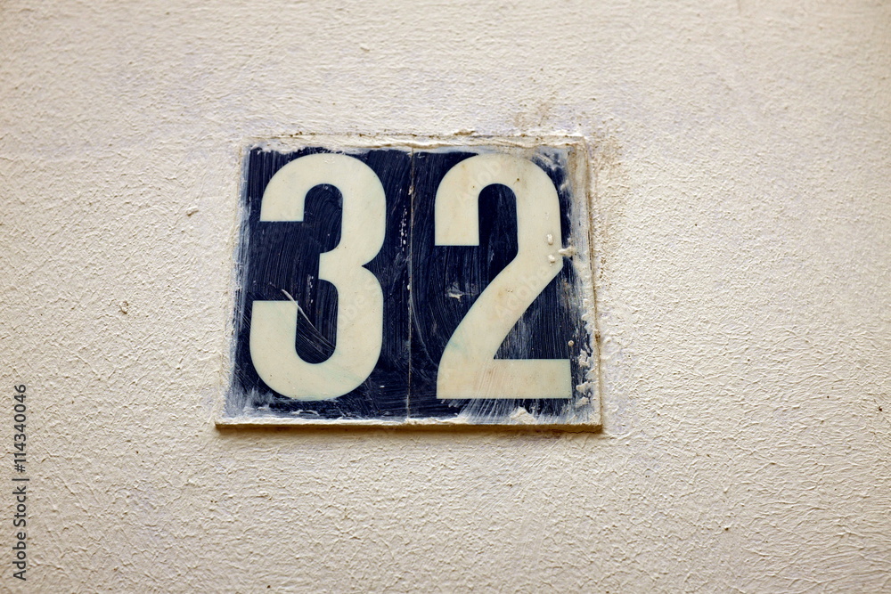 Numéro 32. Chiffres bleu et blanc sur mur blanc. Numéro 32. Chiffres bleu et blanc sur mur blanc.