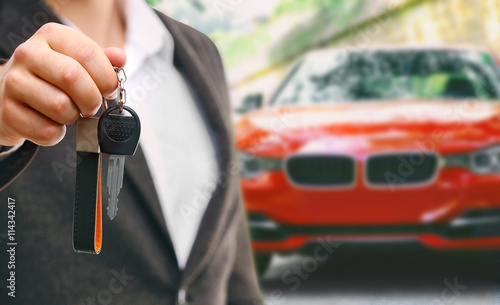 Businessman holding car key on blurred red car background
