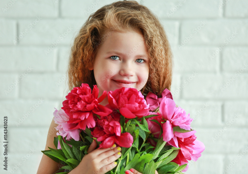 Beautiful girl holding fresh peonies bouquet on brick wall background Beautiful girl holding fresh peonies bouquet on brick wall background