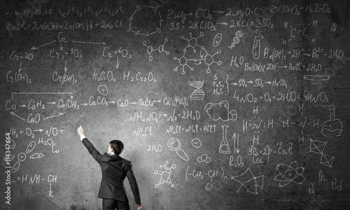 Scientist writing formulas on chalkboard