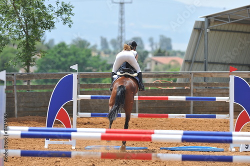 The side view on the rider overcomes the obstacle on the horse jumping competition