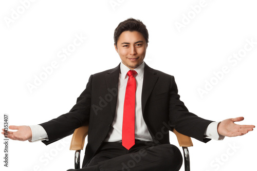 Принти на полотні Handsome carefree businessman in a black suit and red tie, leaning back in a chair against a white background looking directly at camera