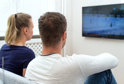 Couple watching hockey match on tv.